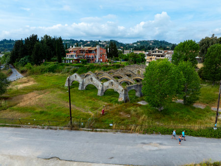 Picturesque landscape featuring the ruins of an arched structure on lush terrain under a bright sky.の写真素材