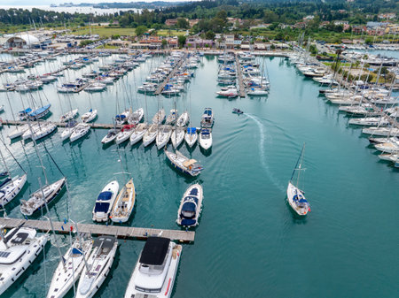 Aerial view captures sailboats and yachts docked in a marina, reflecting in calm water. Serene scene.の写真素材