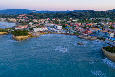 Panoramic aerial view of a coastal resort town with hotels, cliffs, and blue ocean waters at sunset.