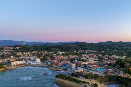 Picturesque coastal village nestled against a verdant hillside at twilight, bathed in soft light.
