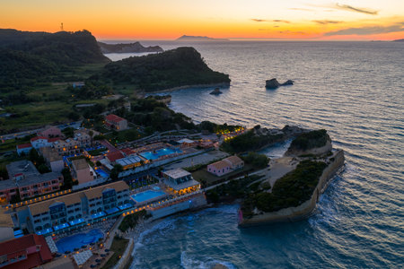Sunset over a coastal resort town featuring hotels, pools, and scenic ocean rock formations.の写真素材