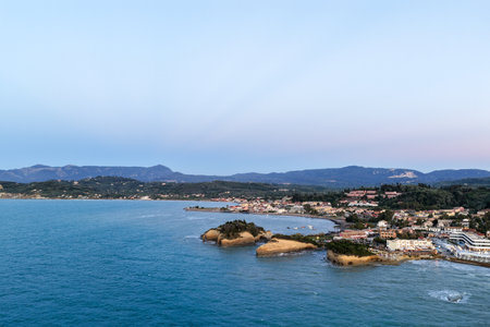 Coastal town nestled along turquoise waters with mountains meeting the skyline in the distance.の写真素材
