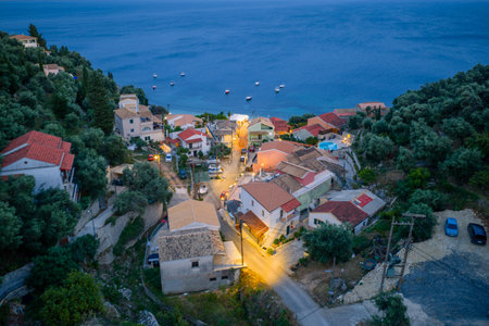 Aerial view of a coastal village nestled between lush greenery and the sea during dusk. Serene scenery.の写真素材