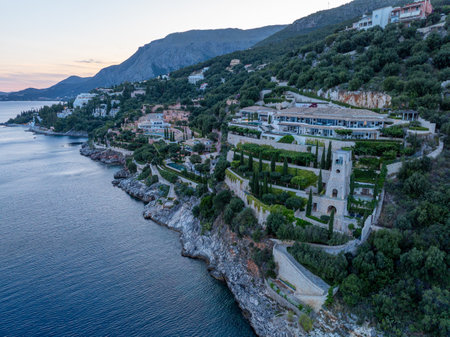 Aerial shot showcases a grand coastal estate nestled on a lush, green hillside with stunning sea views.の写真素材