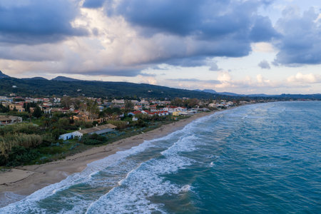 Aerial view of Acharavi coastal town in Corfu, Greece, with rough sea waves and dramatic cloudy sky.の写真素材