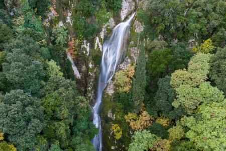 Majestic Hidden Forest Waterfall Cascading Through Lush Greenery and Autumn Foliage from Aerial View â Serene Nature Landscape, Pristine Wilderness, Scenic Mountain Stream and Vibrant Seasonal Colors in Untouched Woodlandの写真素材