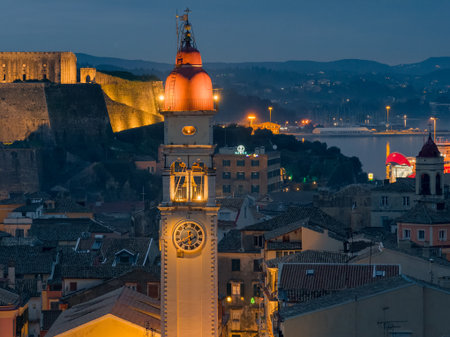 Telephoto Night Detail of Saint Spyridon Clock Tower with Red Dome Against the Illuminated Walls of...