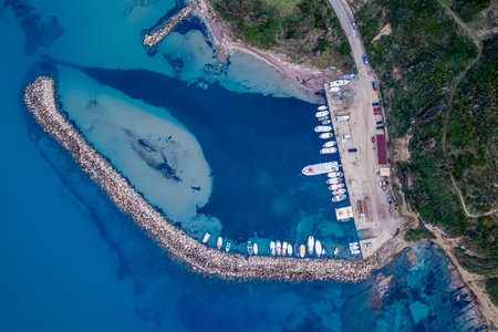 Top down vertical aerial drone view of boats moored at Agios Stefanos marina with clear water and...