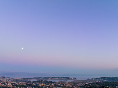 Panoramic sunset view of Corfu island coastline, Greece, featuring dramatic sky, calm Ionian sea, silhouette of mountains, and traditional architecture in a scenic summer landscape travel backgroundの写真素材
