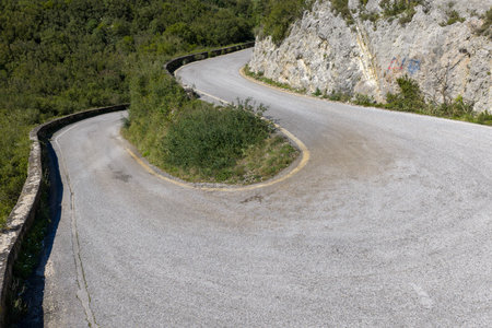Sharp hairpin turn on a winding mountain road with green vegetation and rocky cliffs near Sokraki...