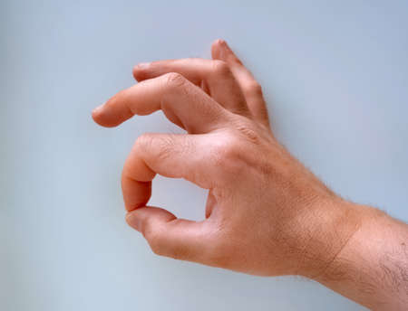 Closed hand with index and middle finger, crossed and a light blue glove, with white background. Luck concept.の写真素材