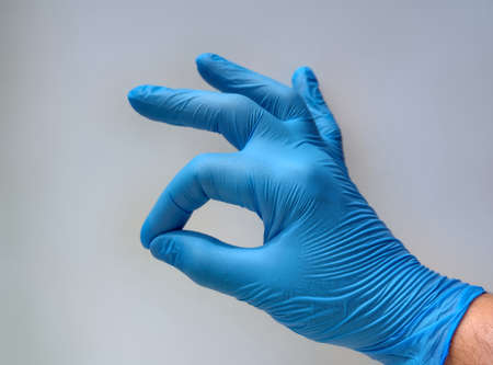 Closed hand with index and middle finger, crossed and a light blue glove, with white background. Luck concept.の写真素材