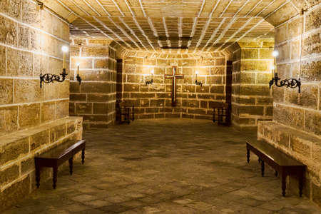 Ancient and dark crypt under an old church, with a multitude of tombs in it.の写真素材