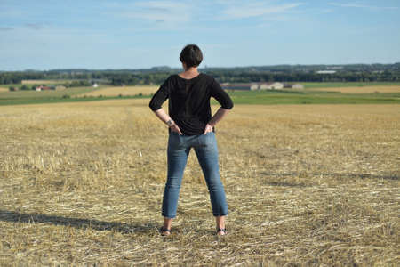 A woman looks at a mown fieldの写真素材