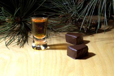 Glass with brandy and sweets against a dark background with pine branches and copyspace.の写真素材
