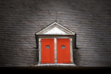 Dormer with red shutters on a slate roofの写真素材