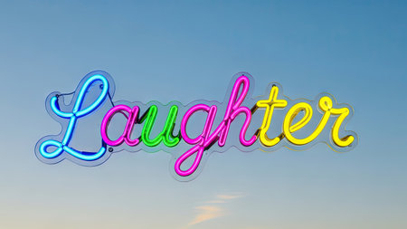 A vibrant neon sign displays the word 'Laughter', illuminated against a clear, gradient blue sky. The sign features a combination of bright colors including blue, pink, green, and yellow, with a retro style. This image could be suitable for various commercial uses, including advertising and editorial content.の素材