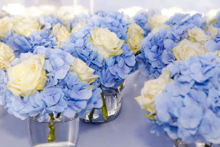 beautiful and delicate bouquet of white rose and blue hydrangea in glasses vaseの写真素材