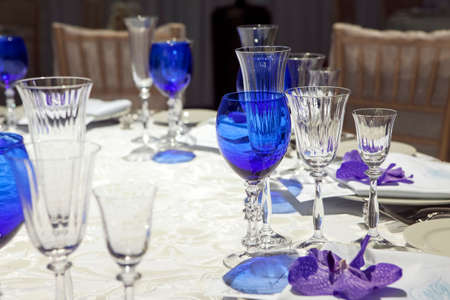 serviette on a plate served on the festive table. Blue goblet and violet orchidの写真素材