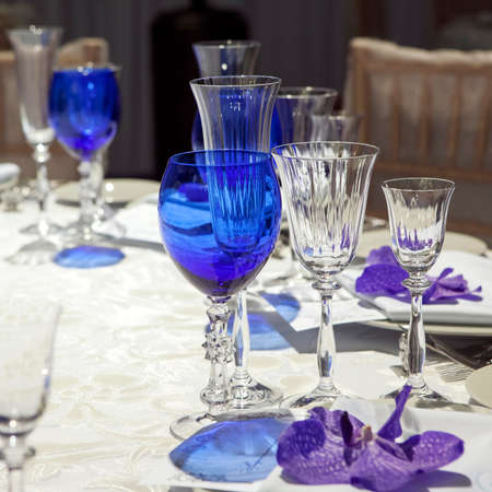 serviette on a plate served on the festive table. Blue goblet and violet orchidの写真素材