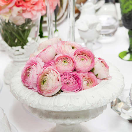decoration of wedding table. pink ranunculus (persian buttercup) in vase on white tableの写真素材