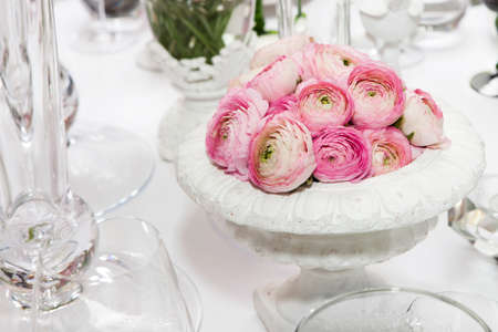 decoration of wedding table. pink ranunculus (persian buttercup) in vase on white tableの写真素材