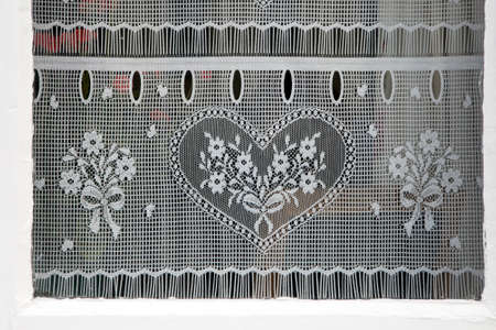 Photo of a lace curtains with heart in the windowの写真素材