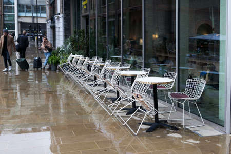 LONDON, UK - JANUARY 30 2016: Part of the exterior of a modern apartment building near Kings Cross station in London. Reflection after rain. Cafe. Tables and chairsのeditorial素材