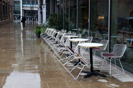 LONDON, UK - JANUARY 30 2016: Part of the exterior of a modern apartment building near Kings Cross station in London. Reflection after rain. Cafe. Tables and chairsのeditorial素材