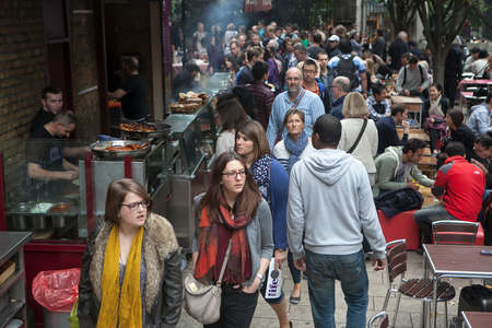 London, England - August 20, 2015: People walk by whilst someone is selling food at stall in Borough Market, London. A market has traded in Southwark, London for more than 250 yearsのeditorial素材