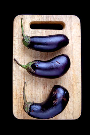 Healthy Organic Eggplant, lying on a wooden board isolated on black backgroundの写真素材