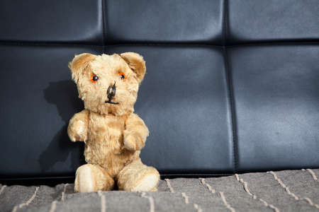 the old vintage teddy-bear sitting on sofaの写真素材