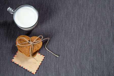 Gift for Valentine's Day. Gingerbread heart-shaped,  Letter in envelope for  a loved one. Cup of milk. Copy spaceの写真素材