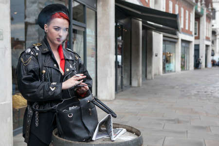 LONDON, UK - August 27, 2016:  girl with red hair dressed in a militaristic style of smokes on the...