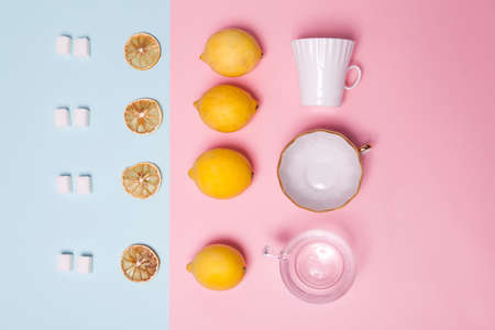 The tea set. Refined sugar, lemon, orange, cups and spoons as an ornament on a pink and blue paper