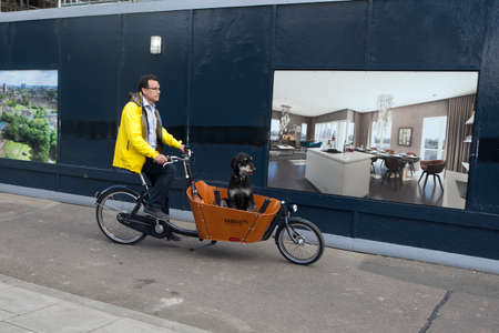 LONDON - August 27, 2016: Man ride on a tricycle with his dog in town. Alternative ecological clean transport in a cityのeditorial素材