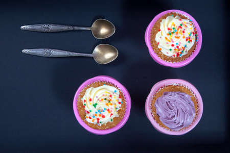 the cupcakes with white and violet cream with spoons on the black background, arranged for a party or a wedding receptionの写真素材
