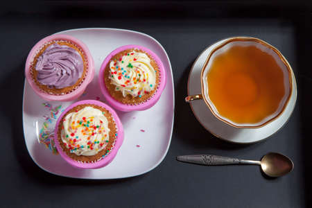 the cupcakes with white and violet cream with spoons on the black background, arranged for a party or a wedding receptionの写真素材
