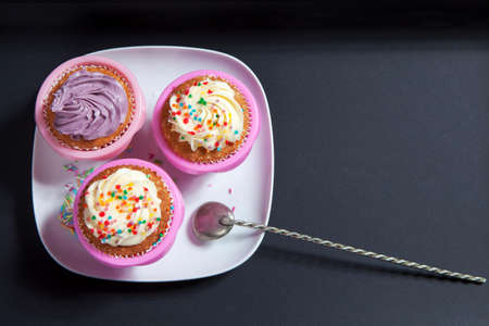 the cupcakes with white and violet cream with spoons on the black background, arranged for a party or a wedding receptionの写真素材