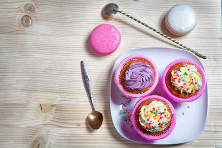 the cupcakes with white and violet cream with spoons on the wooden background, arranged for a party or a wedding receptionの写真素材