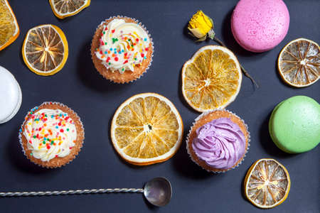 the cupcakes with white and violet cream with spoons on the black background, arranged for a party or a wedding receptionの写真素材