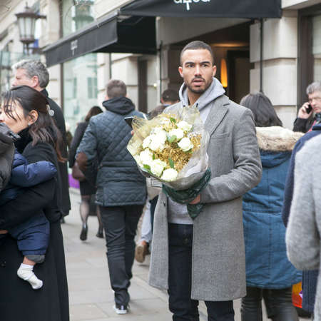 LONDON, ENGLAND - DECEMBER 12, 2016 well-dressed man with a bouquet into the crowdのeditorial素材