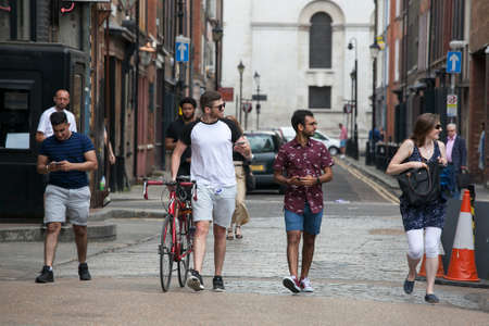 LONDON, UK - August 27, 2016: Men in shorts and a woman in a dress cross the road near Brick Laneのeditorial素材