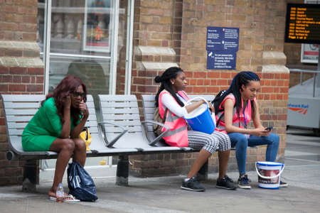 LONDON, ENGLAND - JULY 12, 2016 Tired Girls who collected money for charity, is sitting on a bench near the train station Liverpool stationのeditorial素材