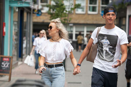 LONDON, ENGLAND - JULY 12, 2016 Happy couple in the white T-shirts, holding hands, walking on the streetのeditorial素材