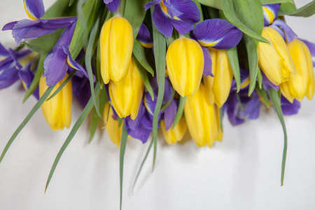 bouquet of yellow tulips and blue irises lying on the wooden floor