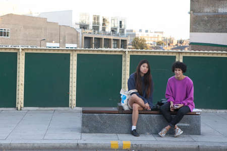 LONDON, ENGLAND - JULY 12, 2016 Two girls sit on a bench on the bridge near Broadway Roadのeditorial素材