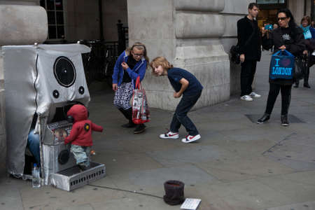 LONDON, ENGLAND - JULY 12, 2016 street children watch an actor who runs a puppet at the discoのeditorial素材