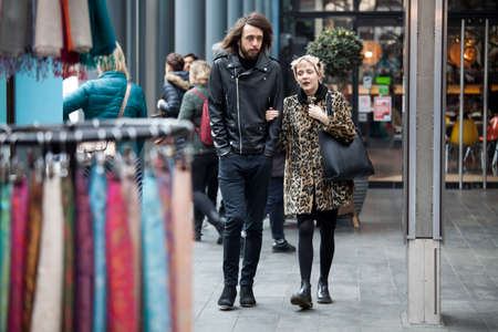 London, UK Thursday March 23, 2017 The couple are walking in the Spitalfield market area against a backdrop of flowering treesのeditorial素材