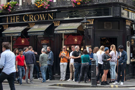 LONDON, ENGLAND - August 11 2017 Men and women drink beer and smoke outside the Crown pub near Leicester square on a sunny dayのeditorial素材